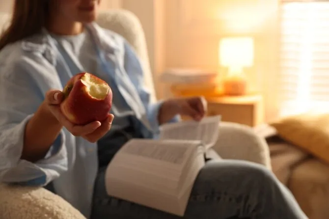 Shutterstock photo/Woman reading a book and eating an apple